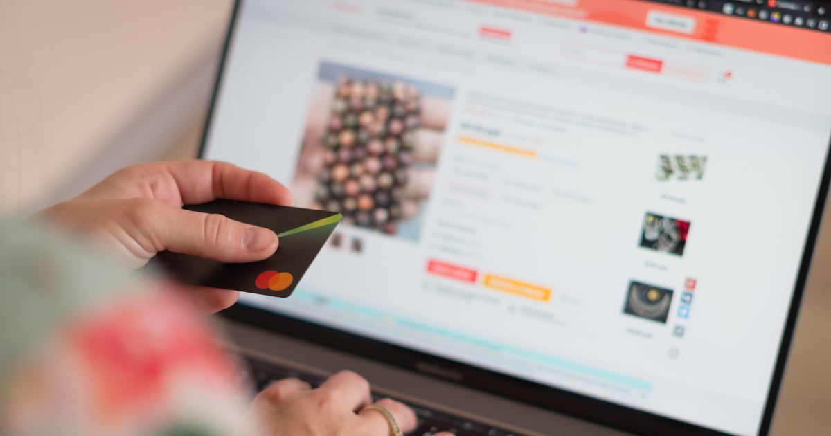 Close-up of a person holding a credit card while browsing jewelry options on an online shopping platform.