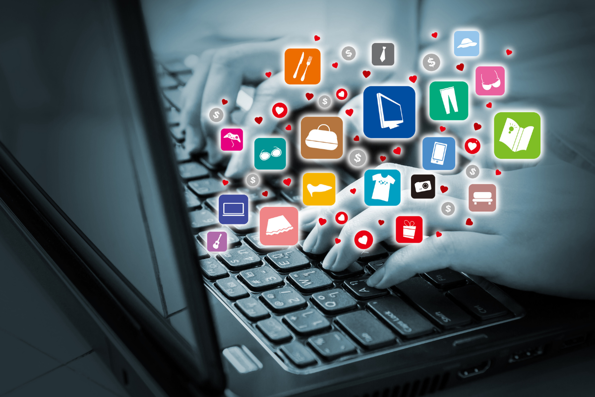 Hands typing on a laptop with colorful shopping and service icons floating above, symbolizing online presence and e-commerce.