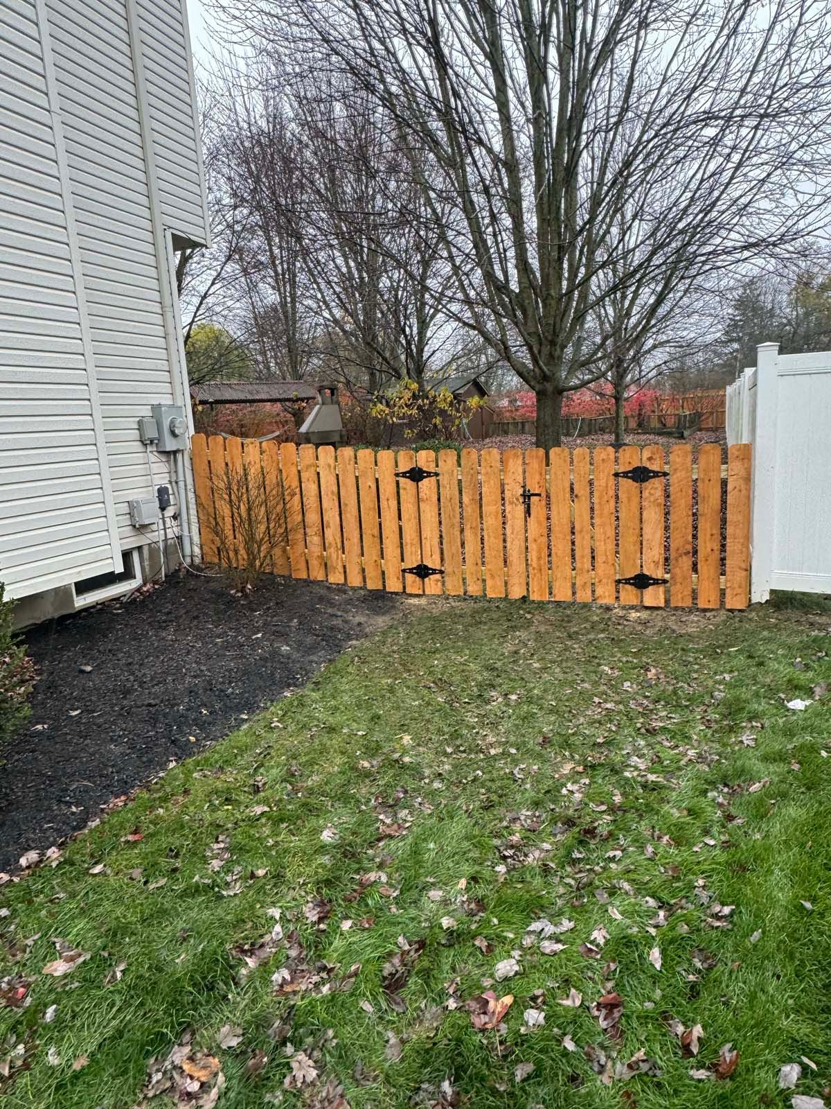 A wooden fence is in the backyard of a house.