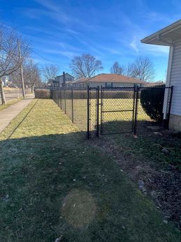 There is a chain link fence in the backyard of a house.