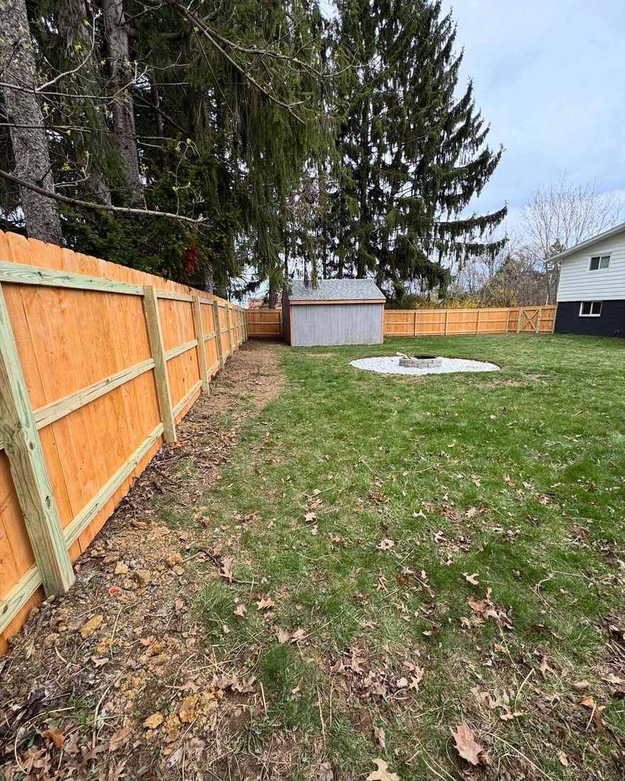 A wooden fence is surrounding a lush green yard.