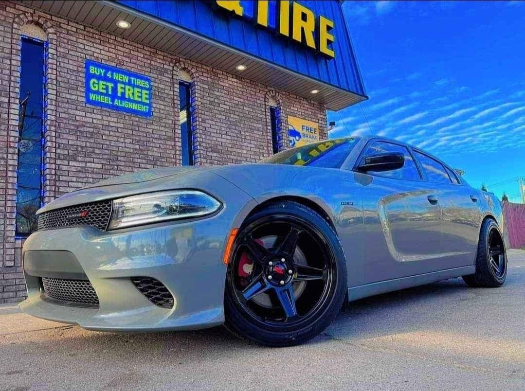 A red dodge challenger is doing a burnout in a parking lot.