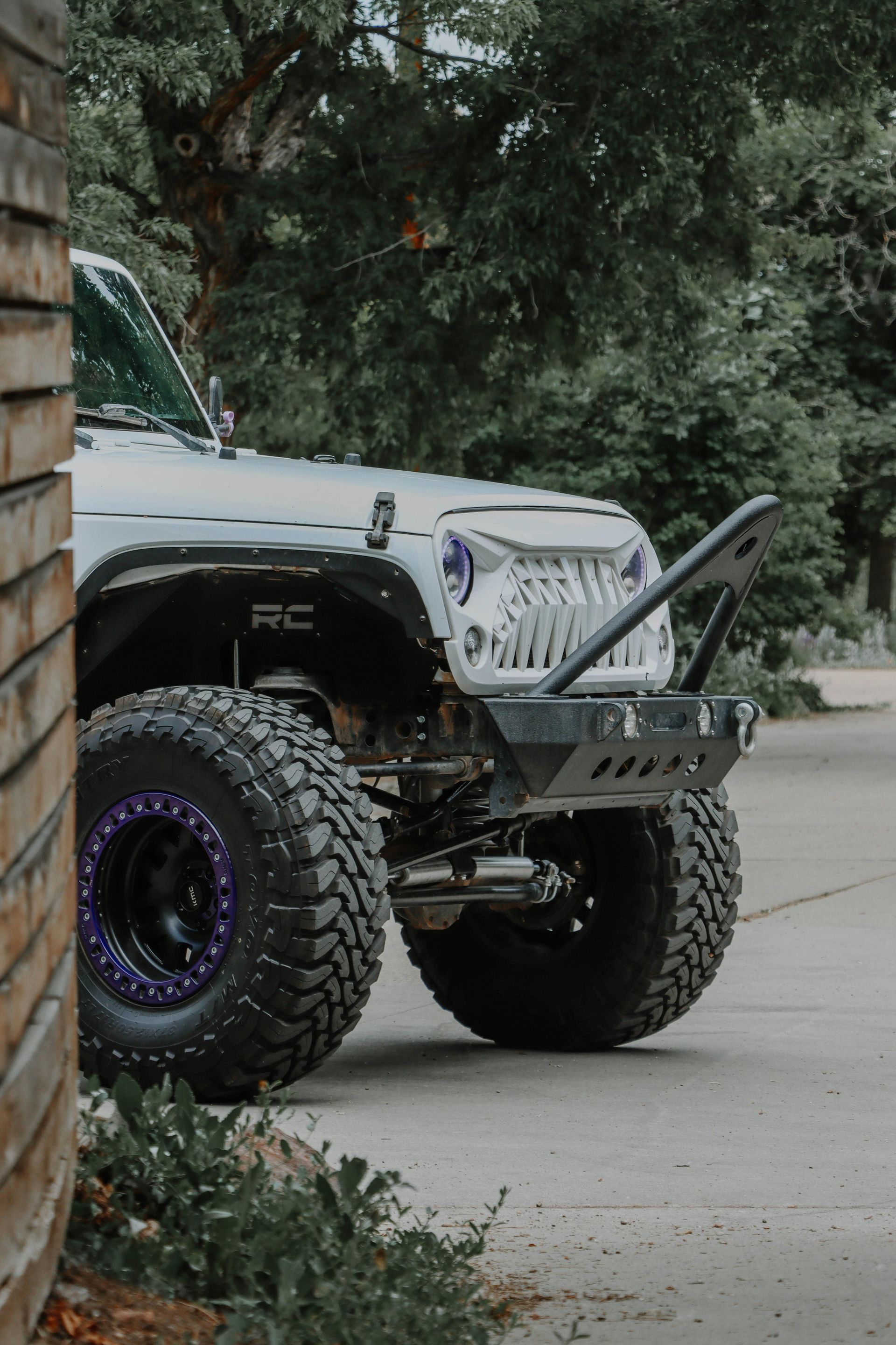 A jeep with purple tires is parked on the side of the road.