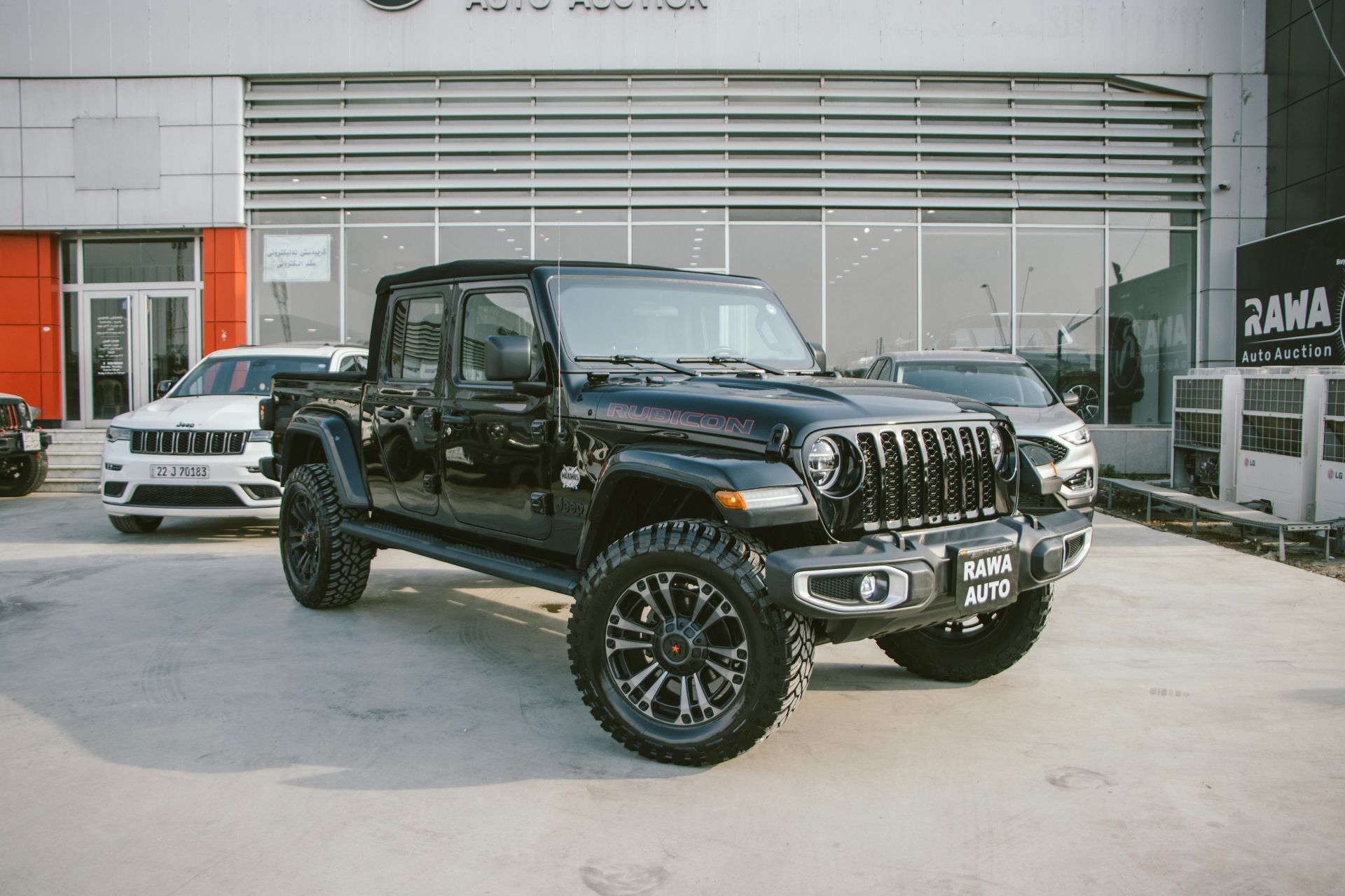 A black jeep wrangler is parked in front of a building.