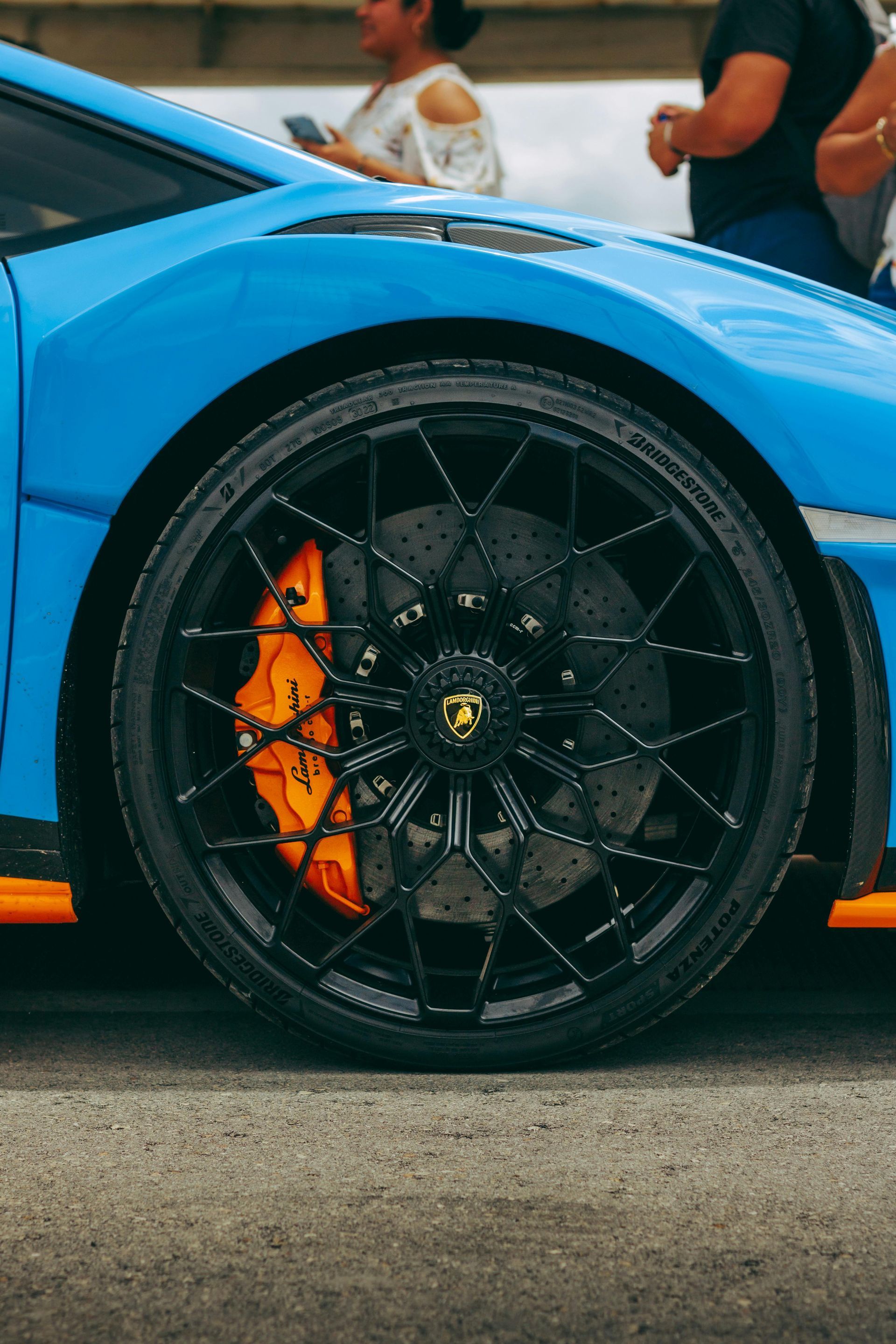 A blue sports car with orange brake calipers is parked on the street.