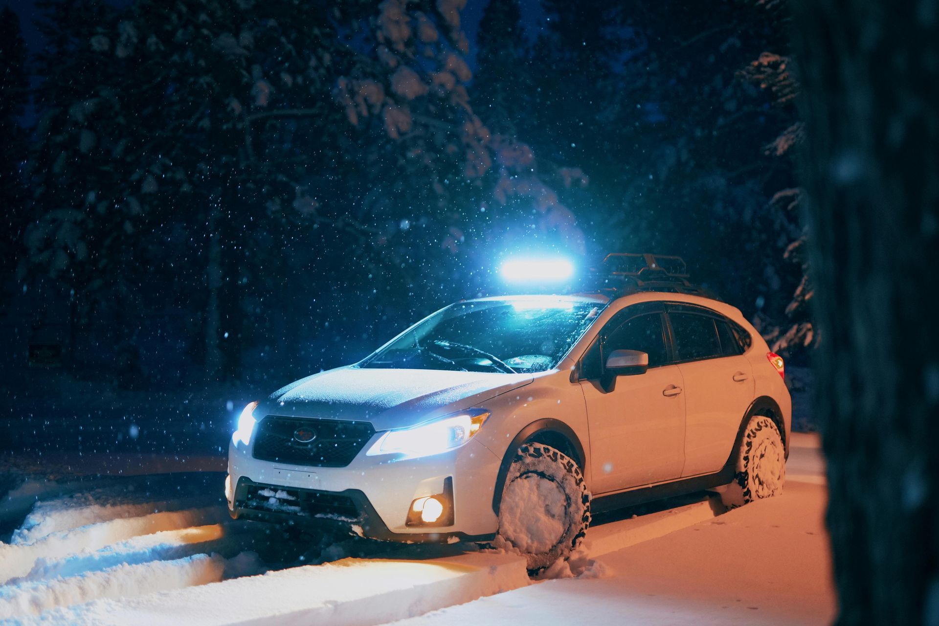 A car with a light on top of it is parked in the snow at night.