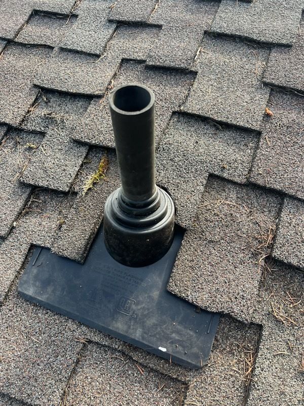 A black pipe is sitting on top of a roof.