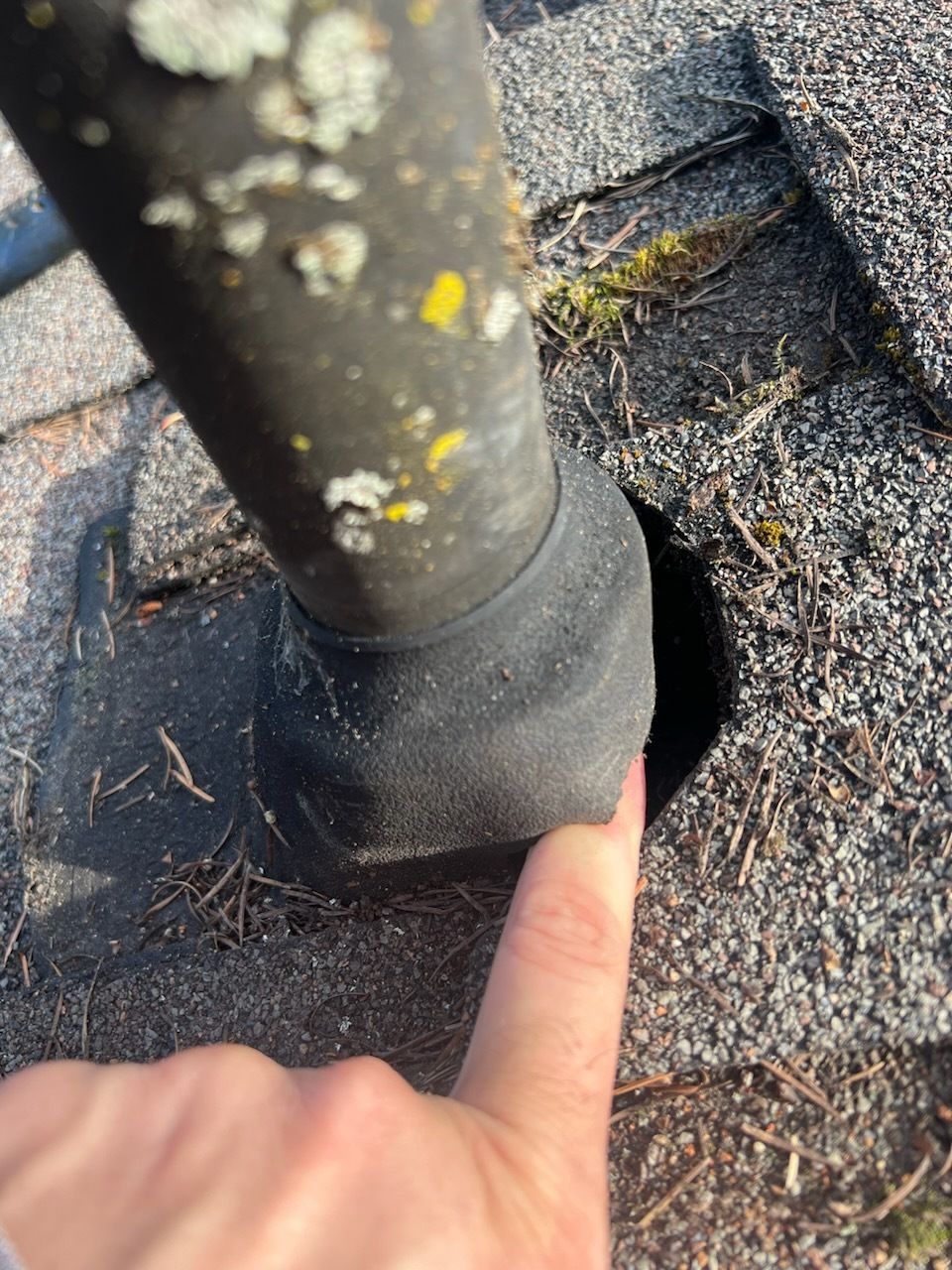 A person is pointing at a pipe on a roof.