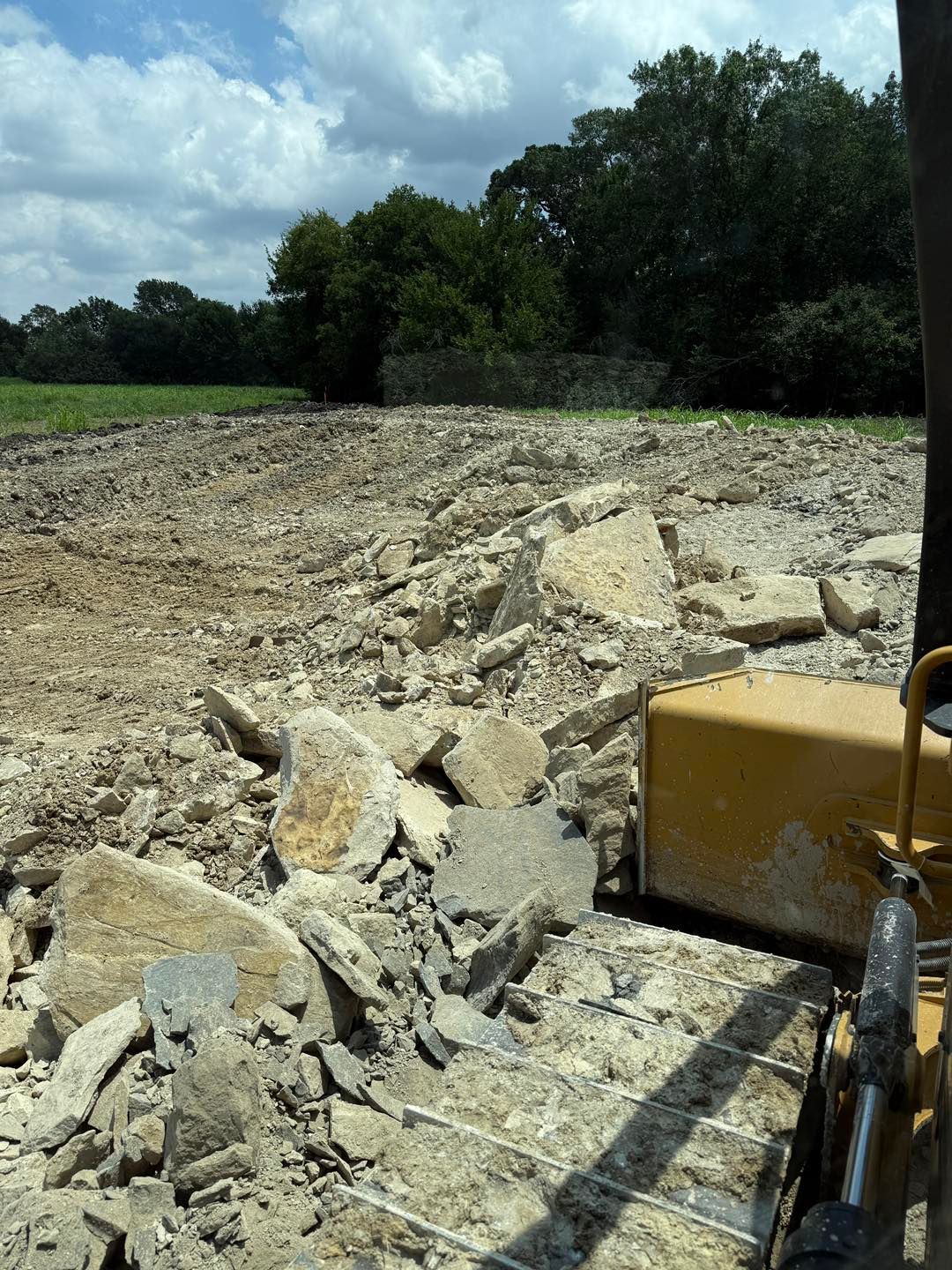 Bulldozer clearing rubble on a construction site under a cloudy sky.