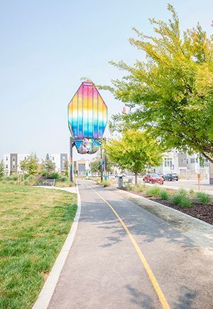 Photo showing artwork in the neighborhood above a walkway/bike path with building in the background
