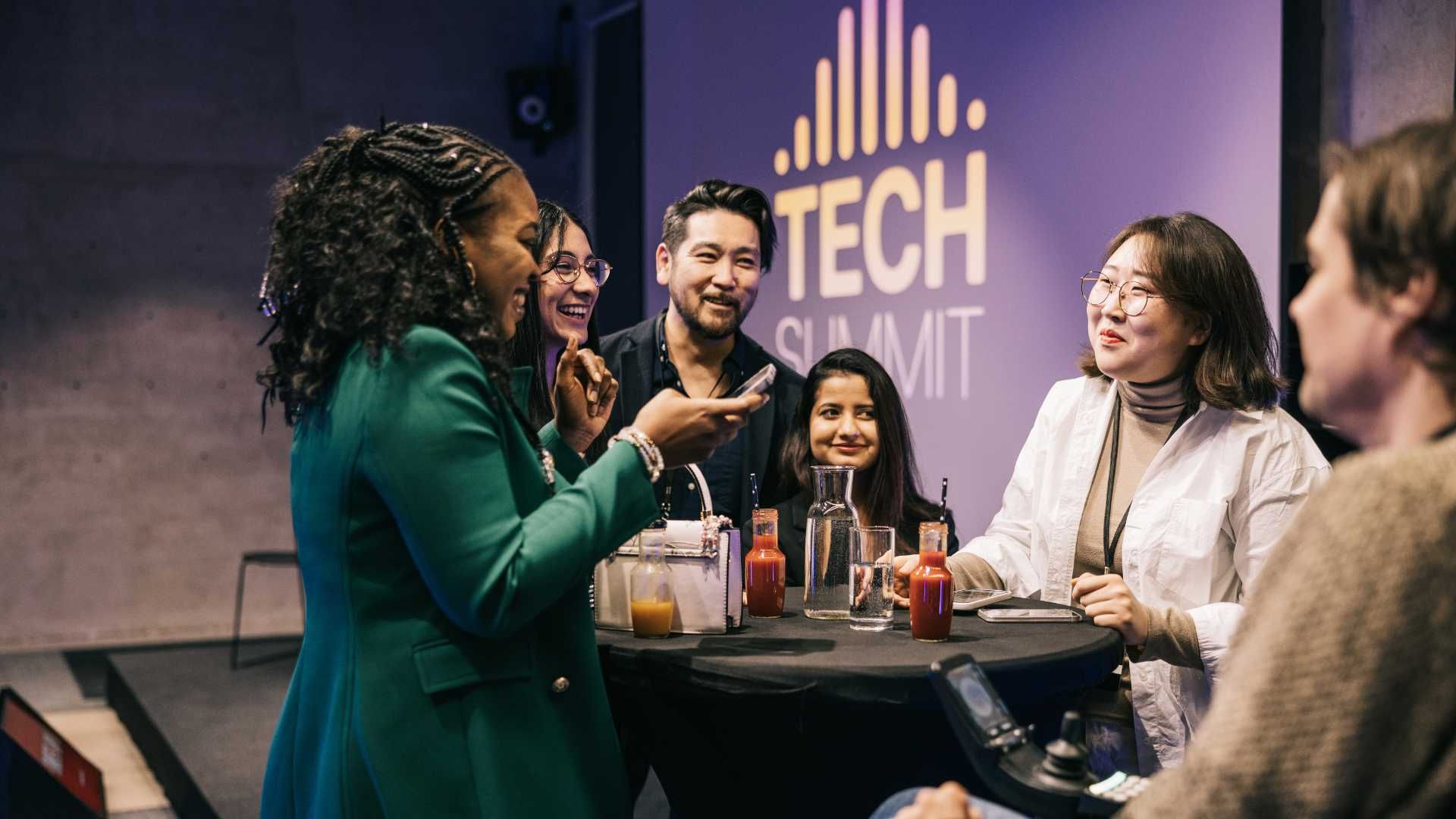A group of people are sitting around a table at a tech summit.
