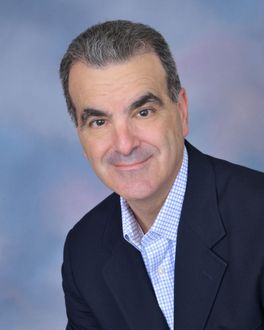 A man in a suit and plaid shirt is smiling for the camera.