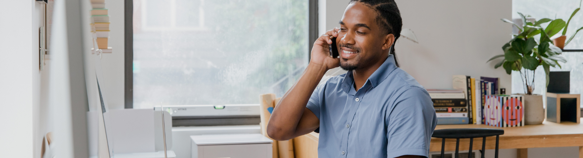 Um homem está sentado em uma mesa falando ao celular.