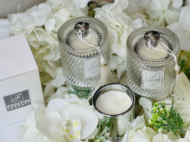 Tre candele sono appoggiate su un tavolo circondato da fiori bianchi.