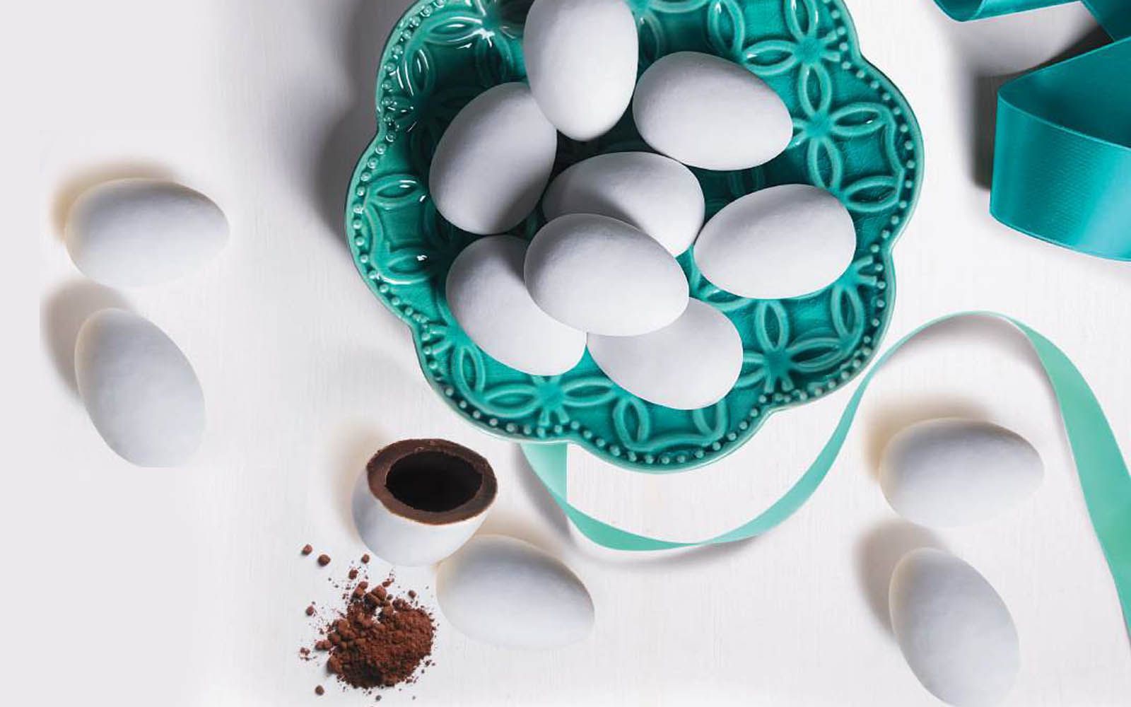 Una ciotola piena di uova bianche accanto a una tazza di cioccolato