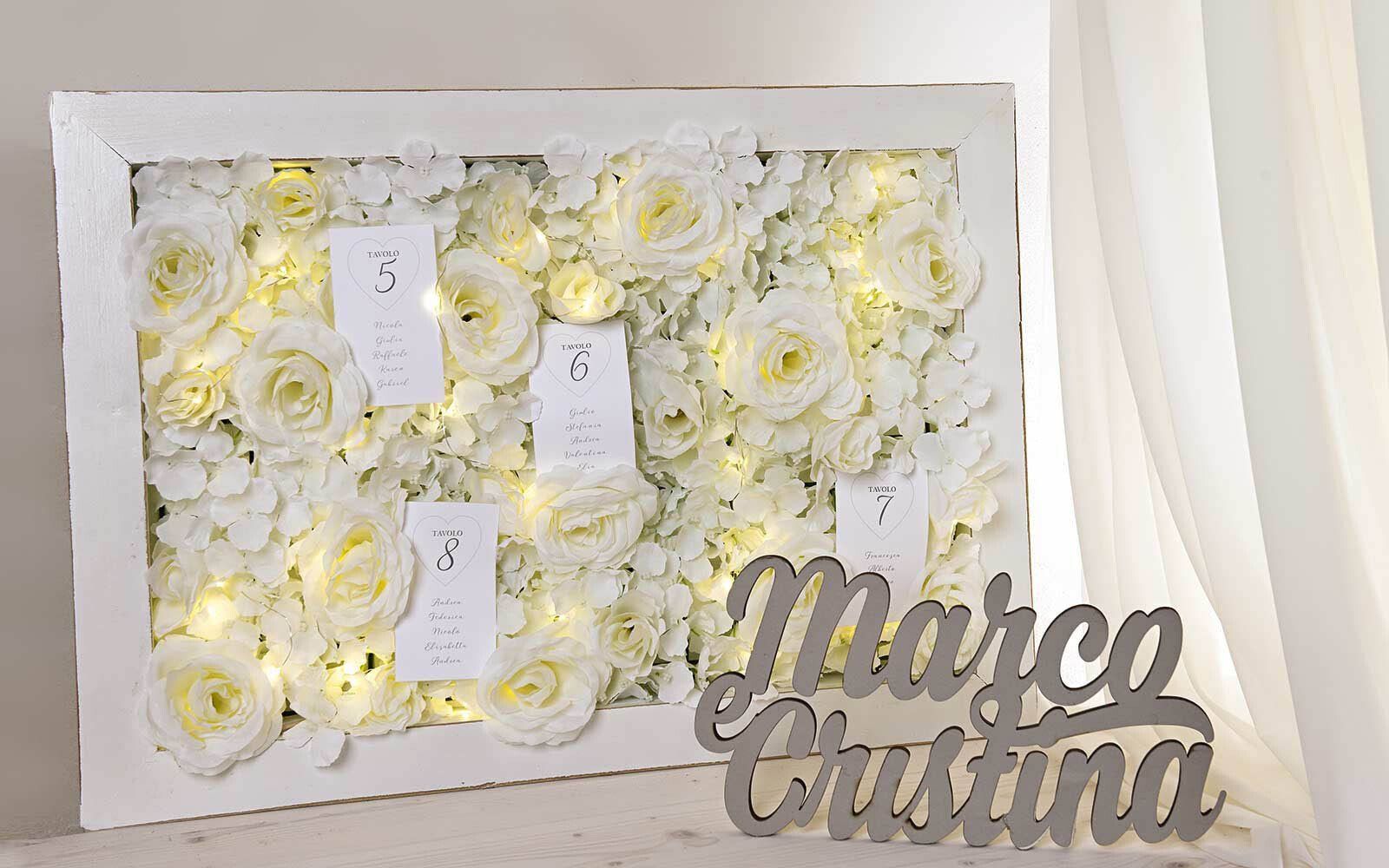 Una cornice piena di fiori bianchi e un cartello con scritto marco cristina