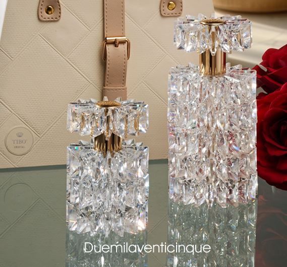 Due bottiglie di profumo sono appoggiate su un tavolo accanto a una rosa