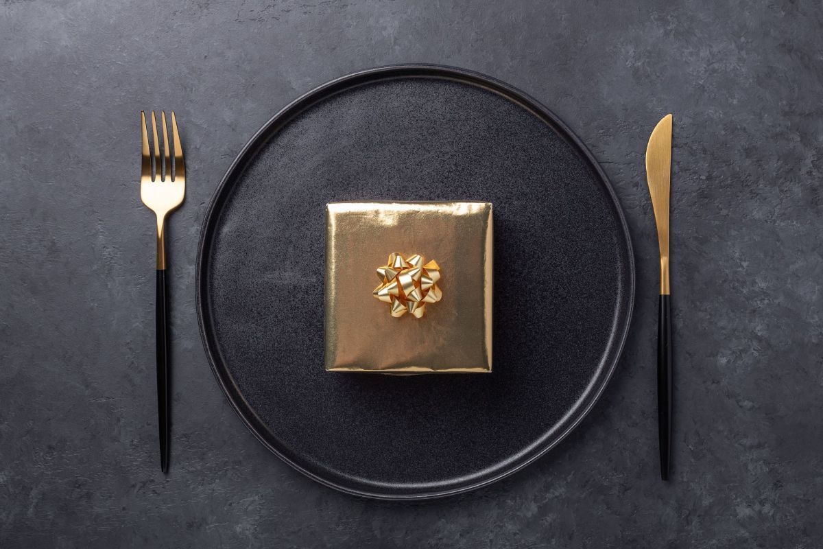 Un piatto nero con una scatola regalo dorata sopra.