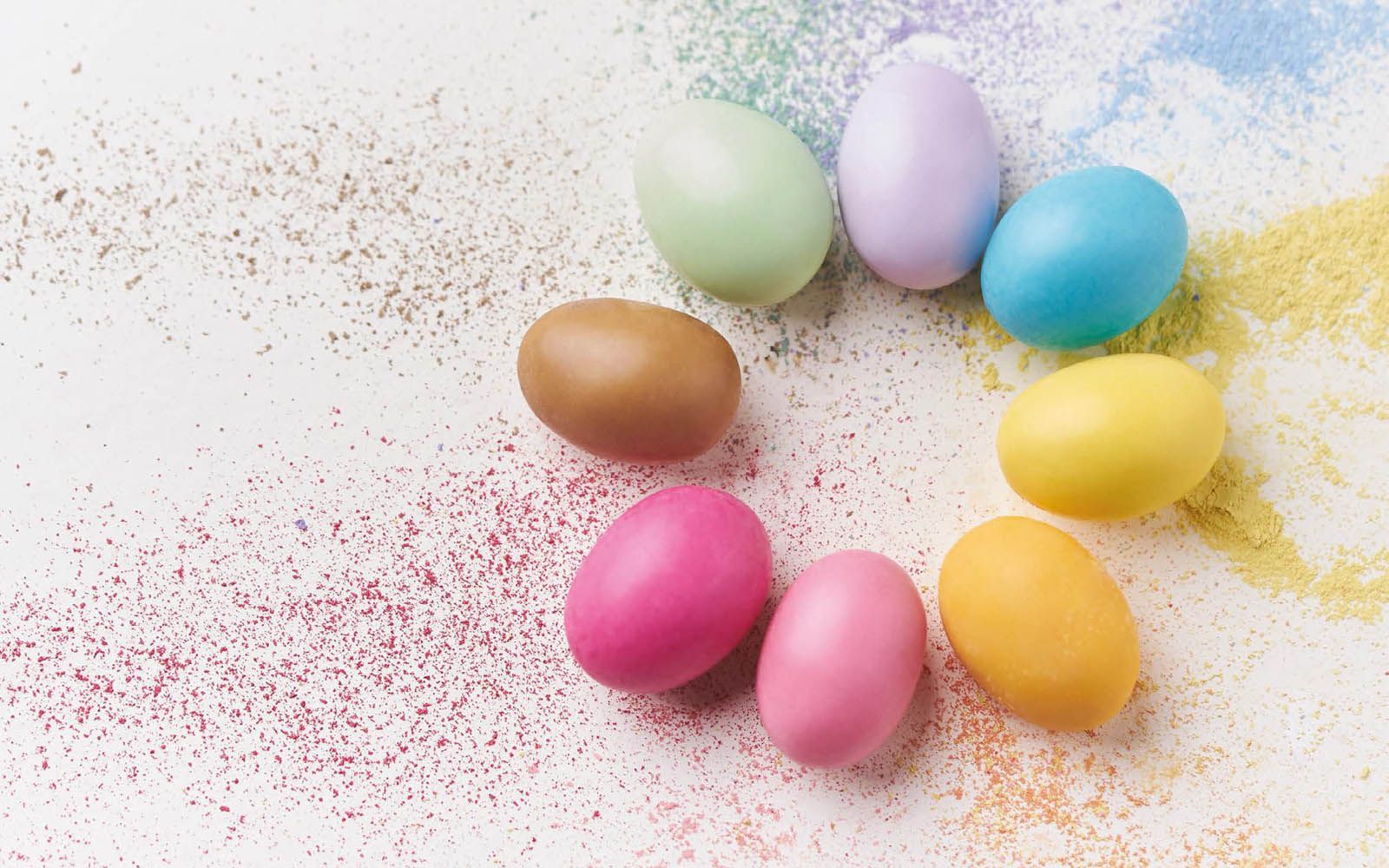 Un cerchio di uova di Pasqua colorate su una superficie bianca.