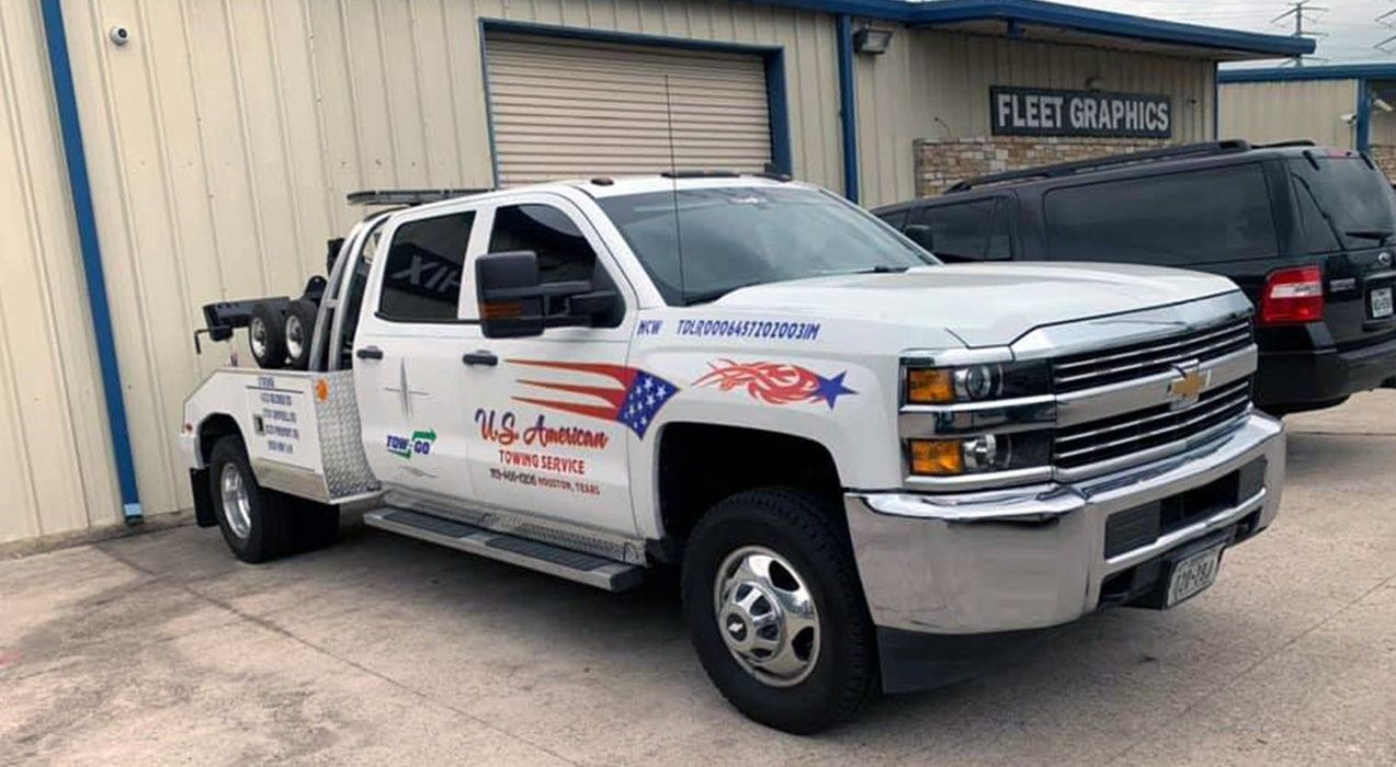 A white tow truck is parked in front of a building.