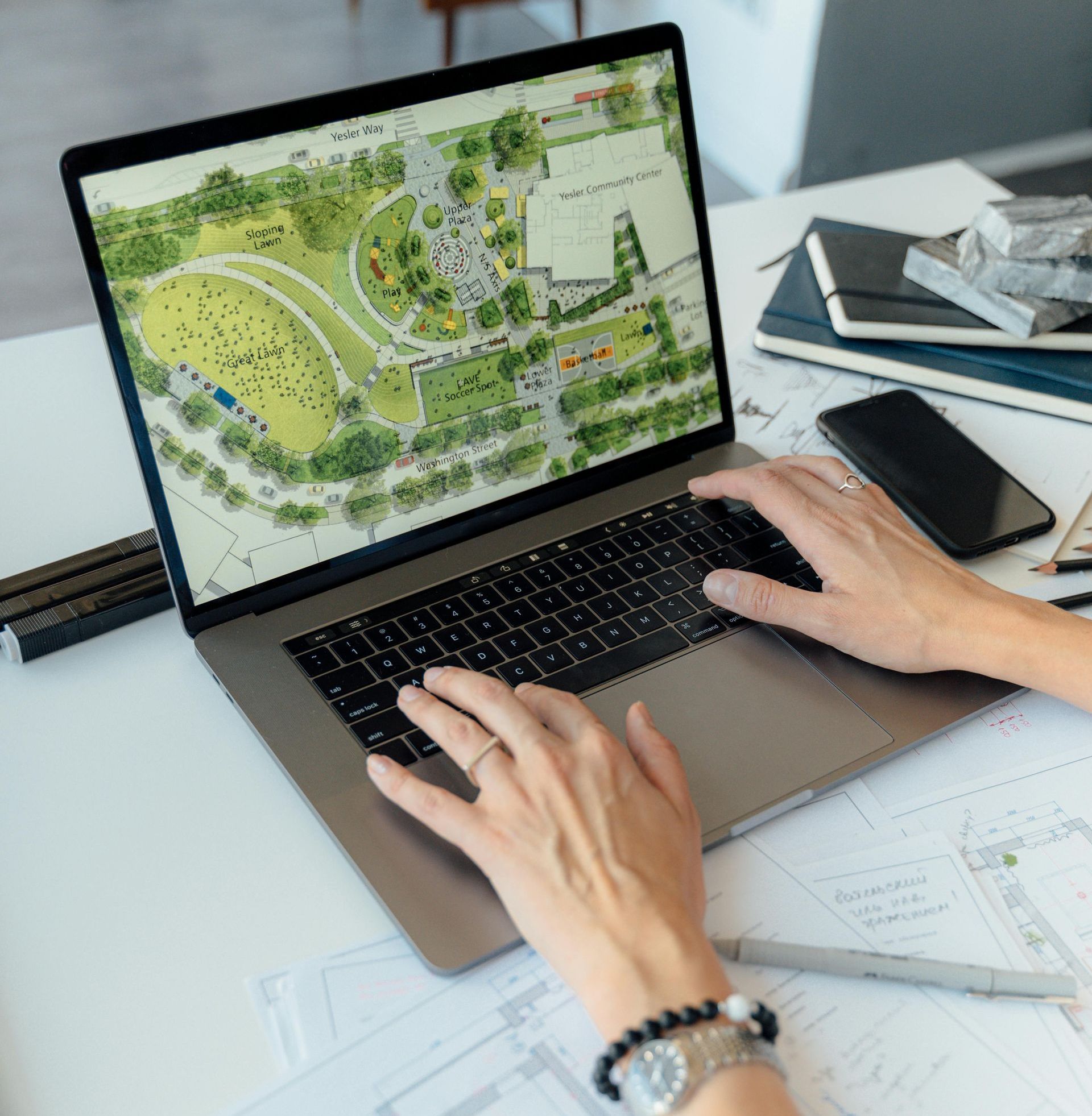 A person is typing on a laptop computer with a map on the screen.