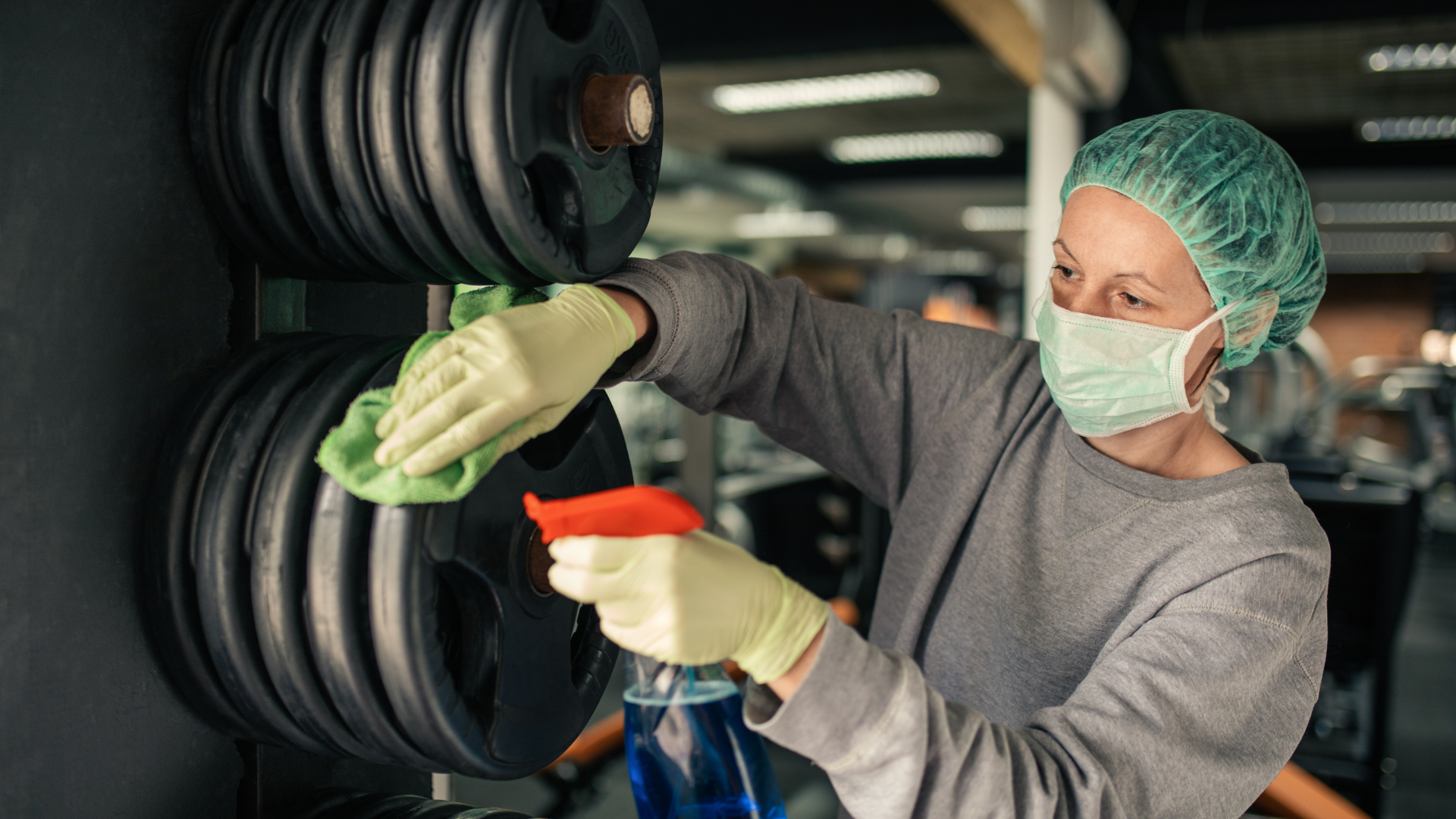 Gym with treadmills, elliptical machines, and weights, featuring large windows and hardwood floors.