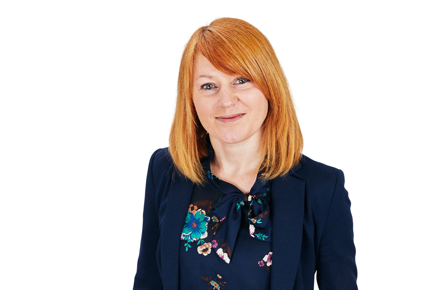 A woman with red hair is wearing a blue jacket and a floral shirt.