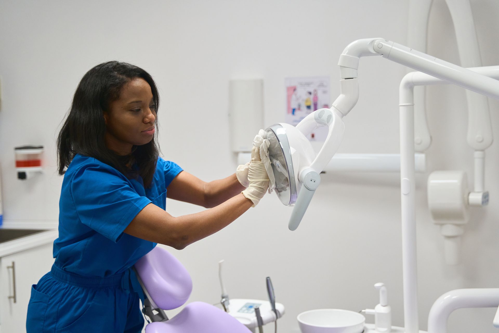 A dental clinic is being cleaned by a woman wearing scrubs.