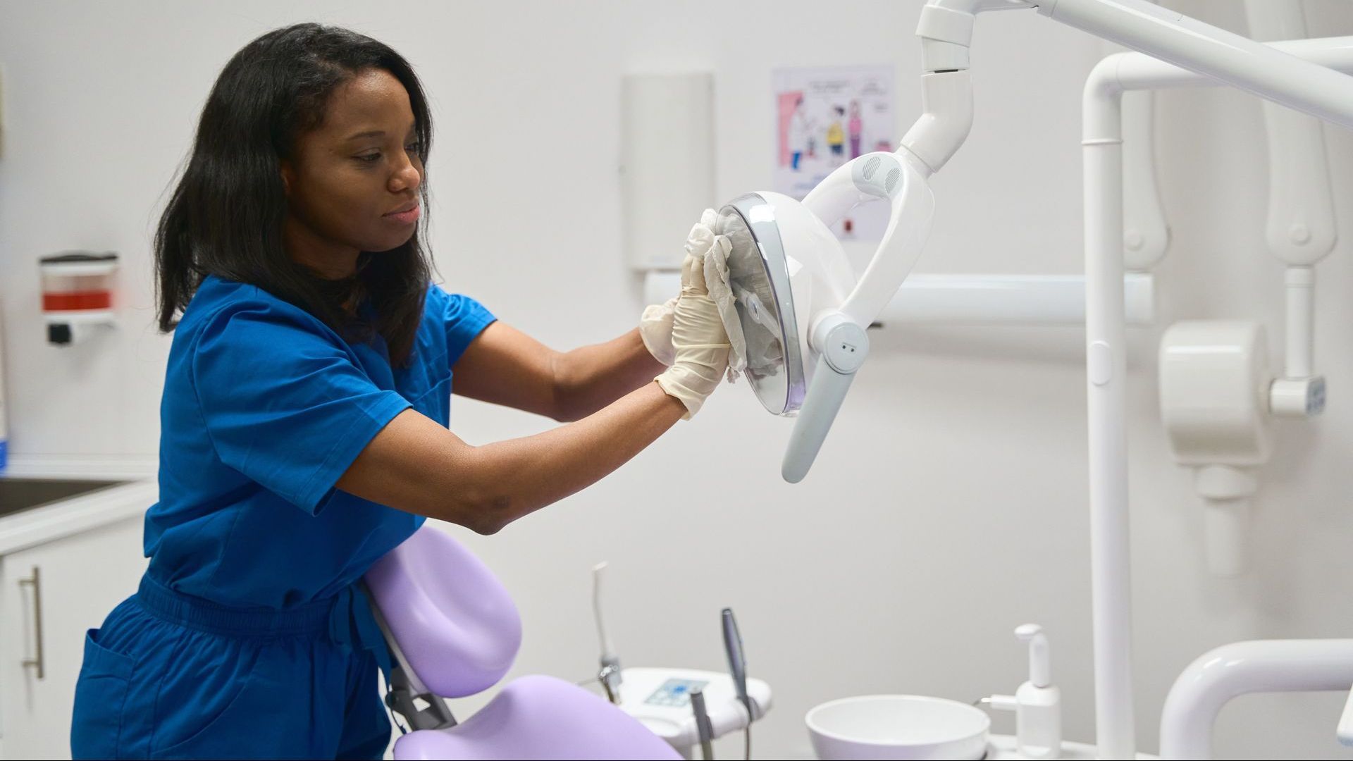 A dental clinic is being professionally cleaned by a woman in scrubs