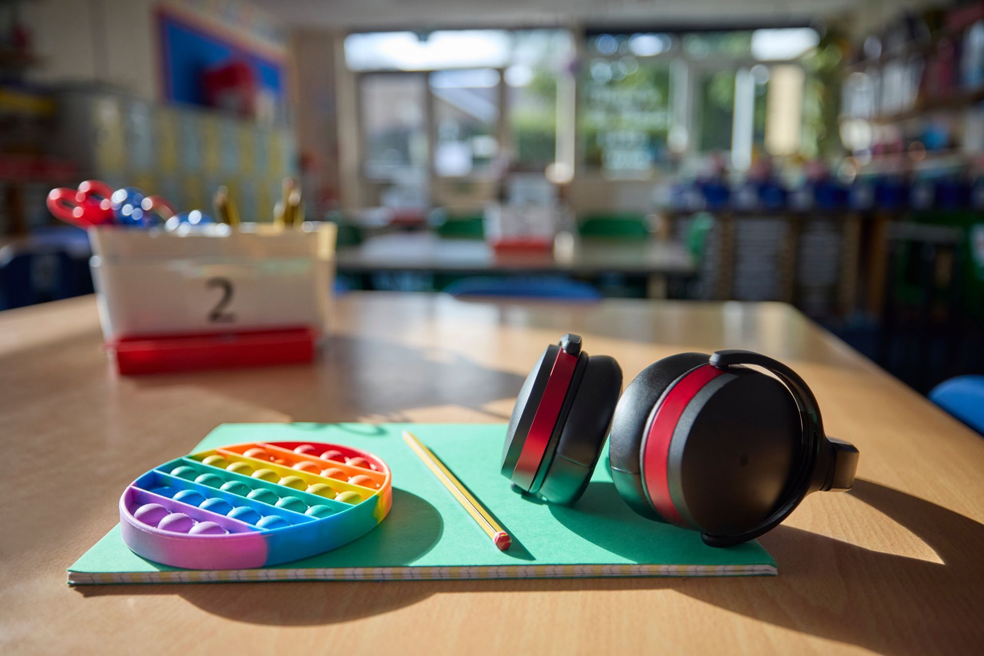Classroom desk with headphones, pop-it toy, pencil, and holder with 