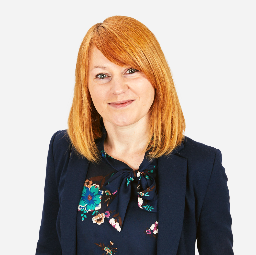 Lady in navy suit with red hair smiling at the camera