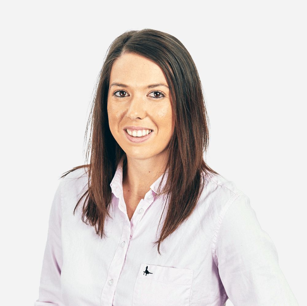 A woman in a pink shirt is smiling for the camera.