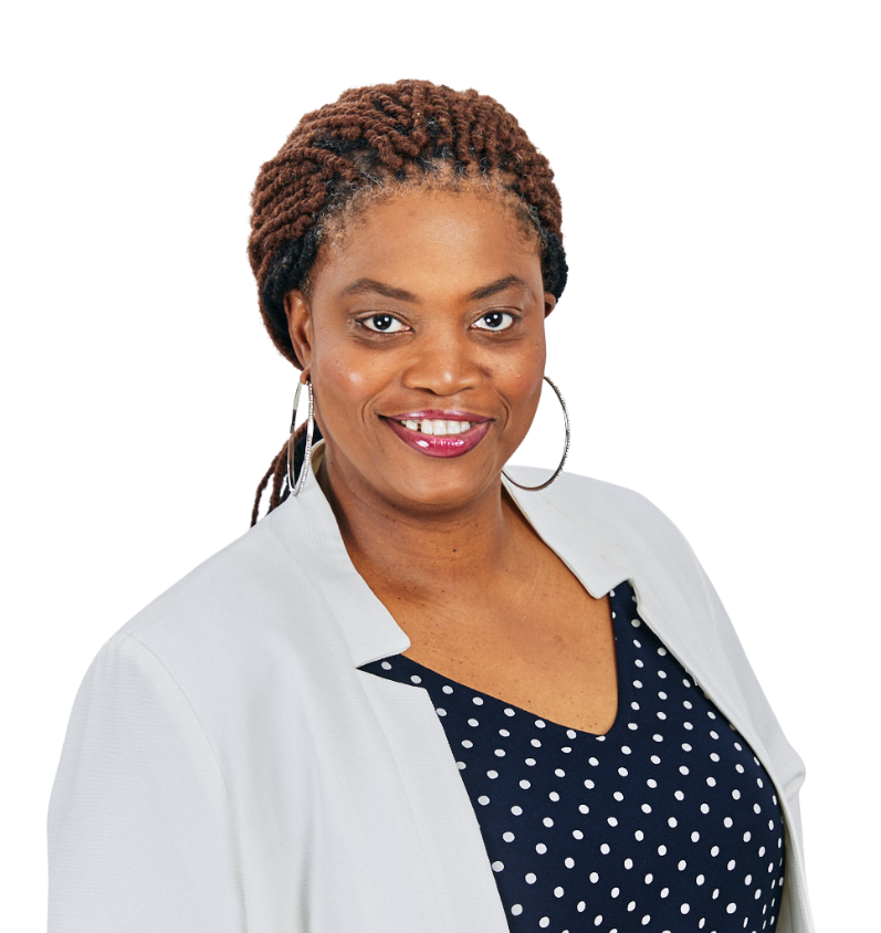 A woman wearing a polka dot dress and a white jacket is smiling for the camera.