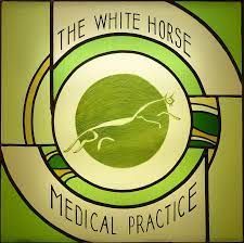 A stained glass window with the logo for the white horse medical practice.