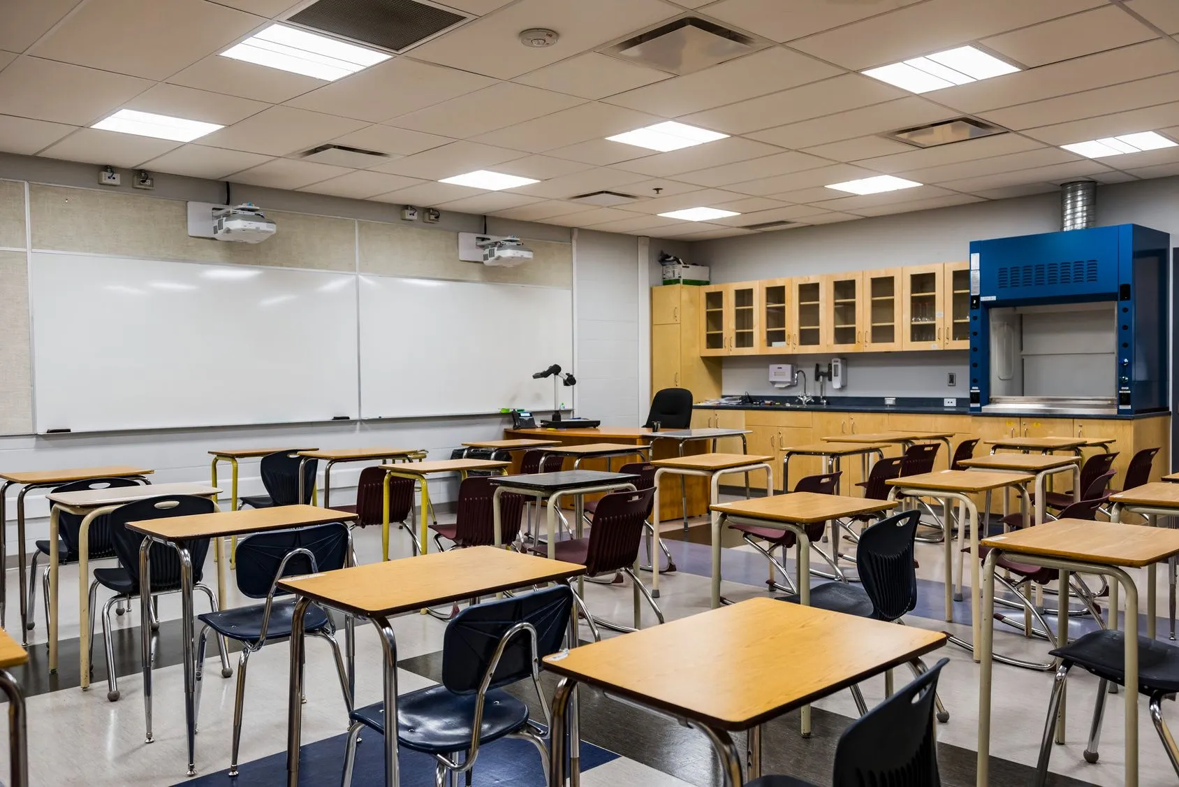 An empty classroom with tables and chairs and a whiteboard.