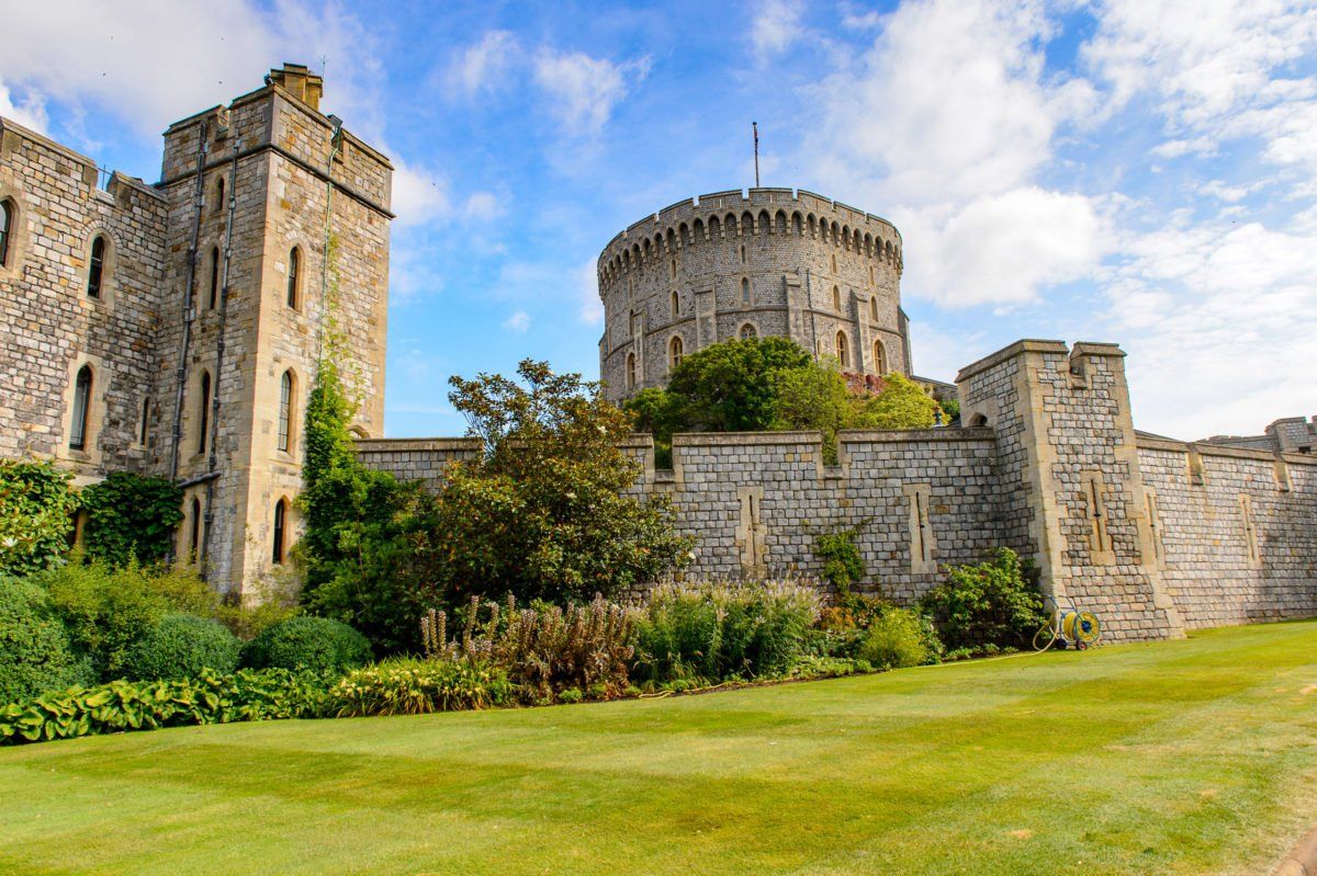 A large stone castle with a tower in the middle of a lush green field.