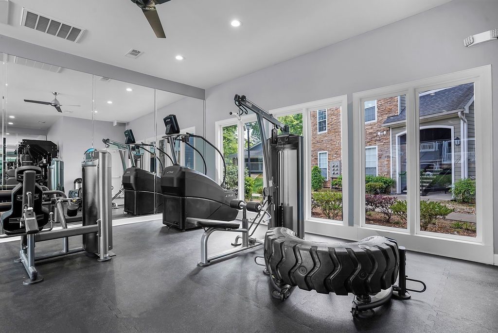 Interior of a modern apartment gym with treadmills, weight machines, and large windows.