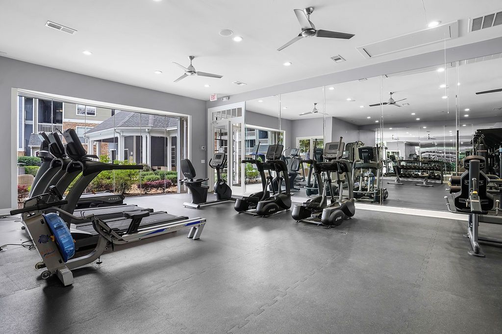 Bright indoor gym with treadmills, ellipticals, and mirrored walls.