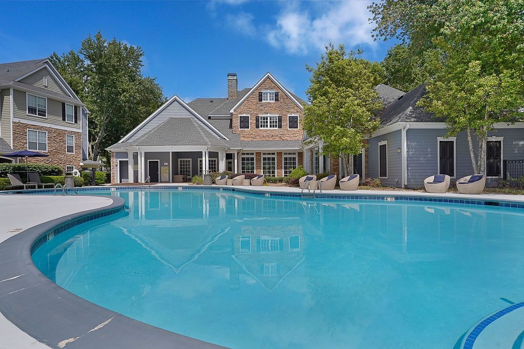 Outdoor community pool with lounge chairs and surrounding residential buildings.