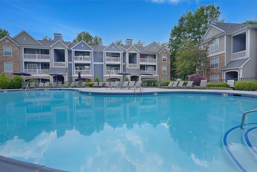 Outdoor apartment pool with lounge chairs and surrounding buildings.