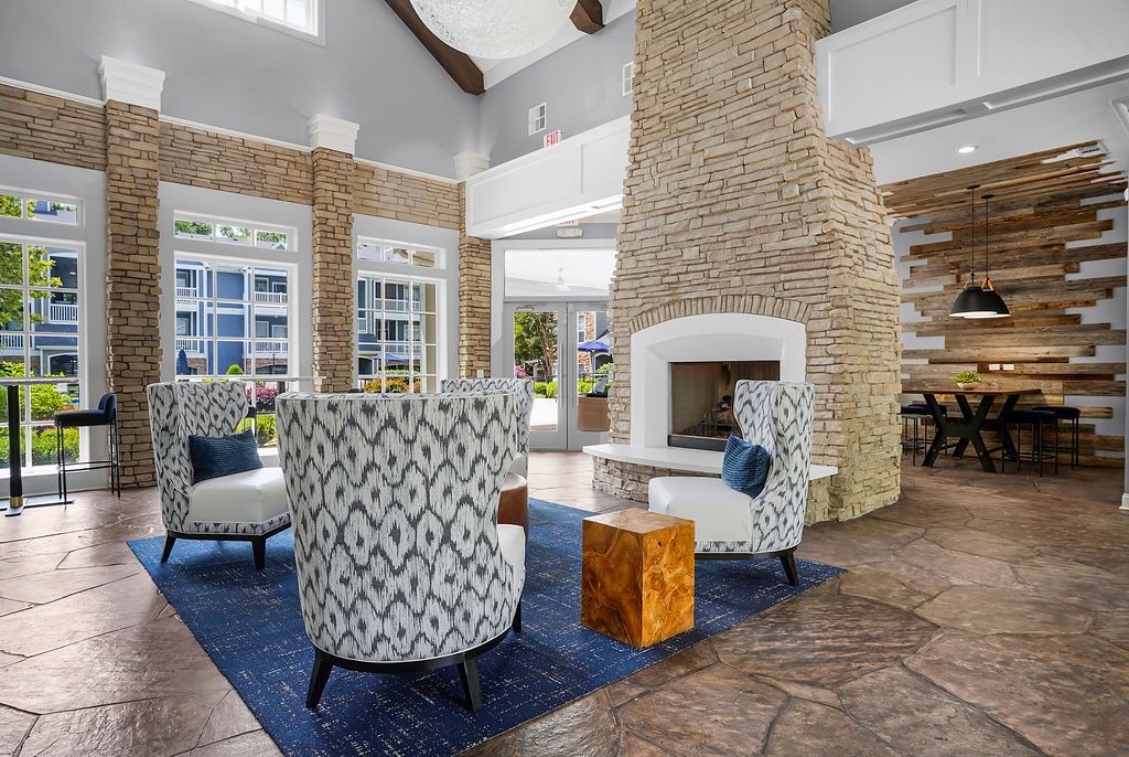 Indoor community lounge with a stone fireplace, modern chairs, and large windows.