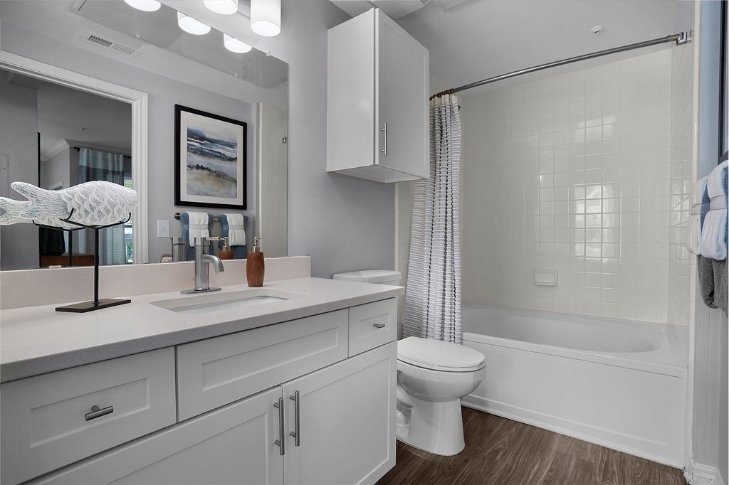 White bathroom with vanity, mirror, toilet, and bathtub/shower.
