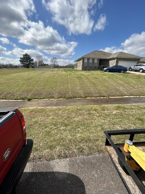 A man is using a lawn mower to cut the grass in a garden.