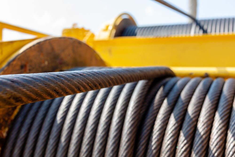 Coiled steel cable on a yellow machine, close-up view.