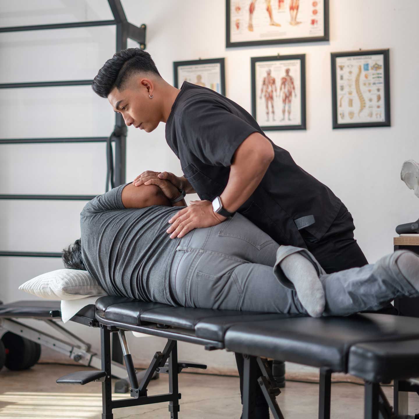 A healthcare professional providing spinal adjustment to a patient lying on a treatment table.