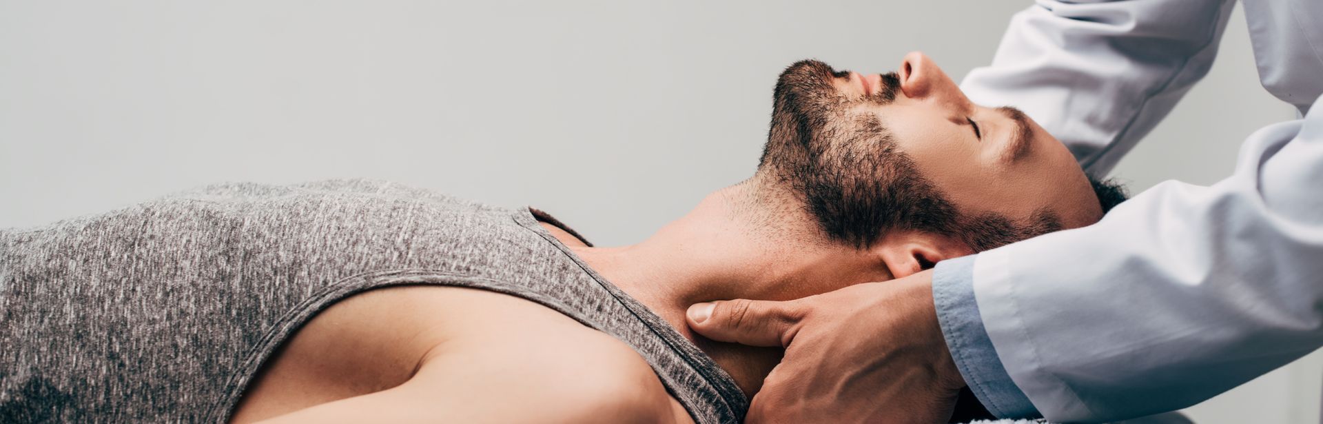 Panoramic shot of a chiropractor massaging the neck of a man on a grey background. Panoramic shot of a chiropractor massaging the neck of a man on a grey background.