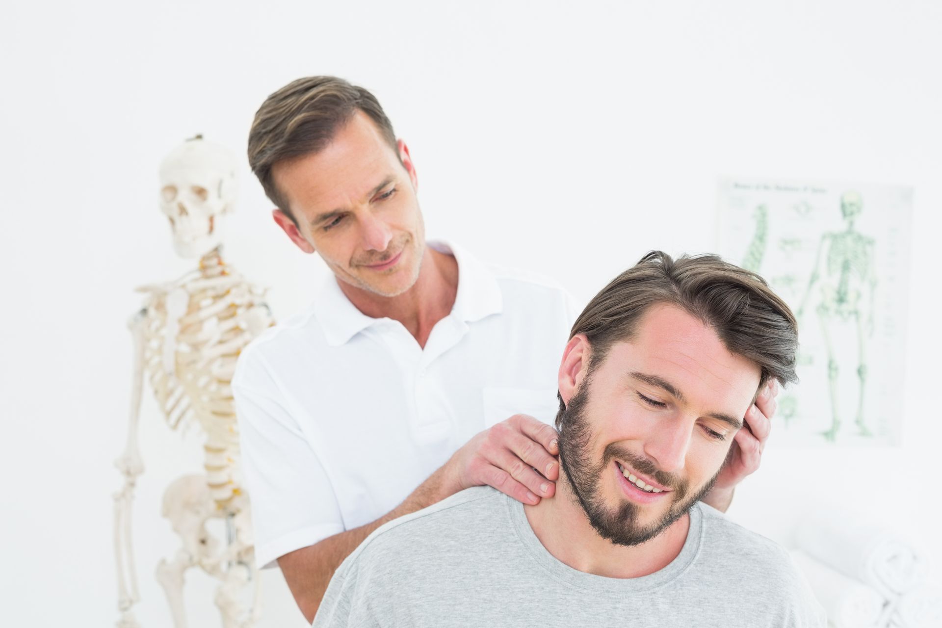 Chiropractor gently supporting a smiling patient's head during a hands-on neck adjustment session.