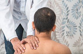 A person receiving a shoulder exam from a medical professional.