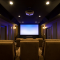 Home theater room with tan recliners, blue ambient lighting, and a large blank projection screen