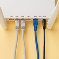 Wi‑Fi router with several Ethernet cables plugged into labeled ports, viewed from the rear.